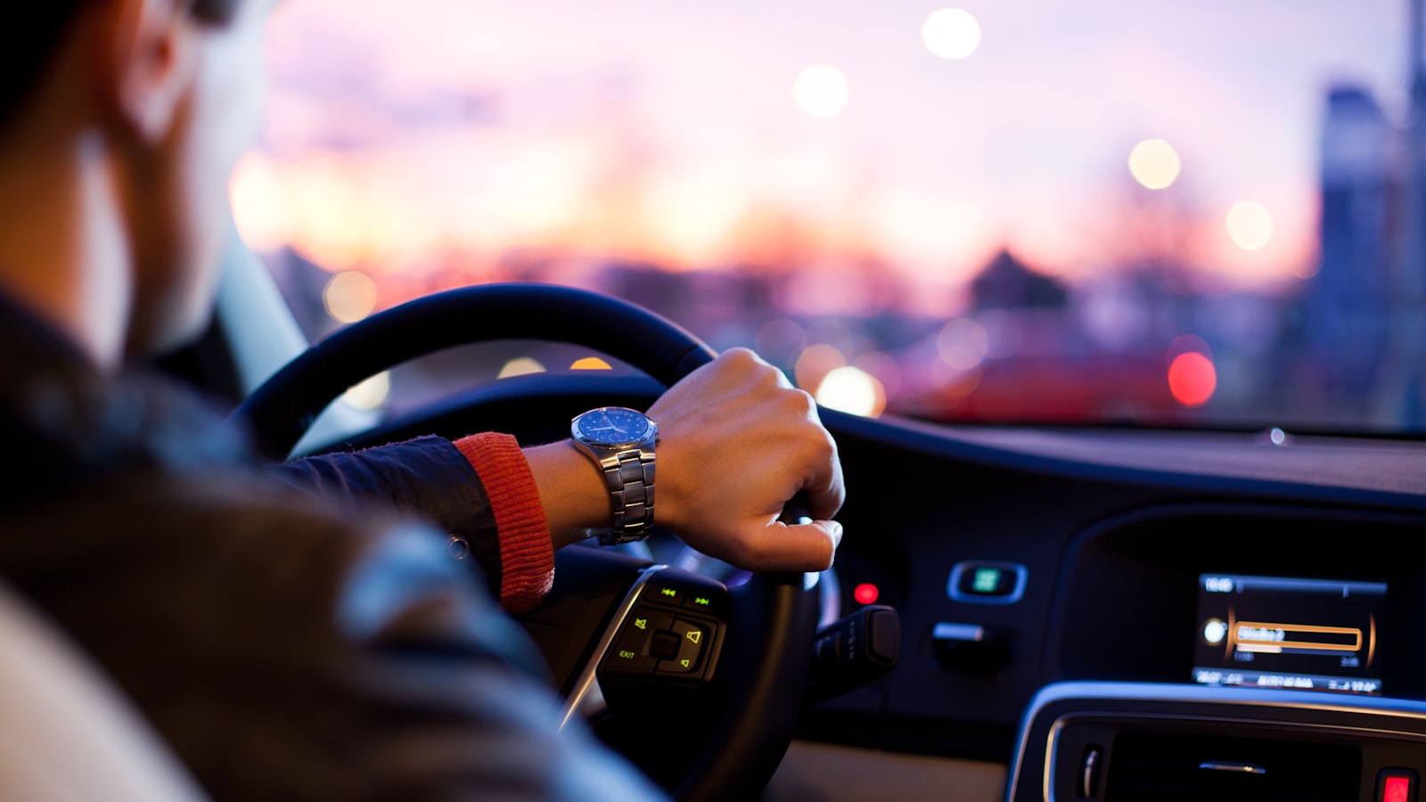 View of a car's steering wheel and dashboard from the driver's seat.