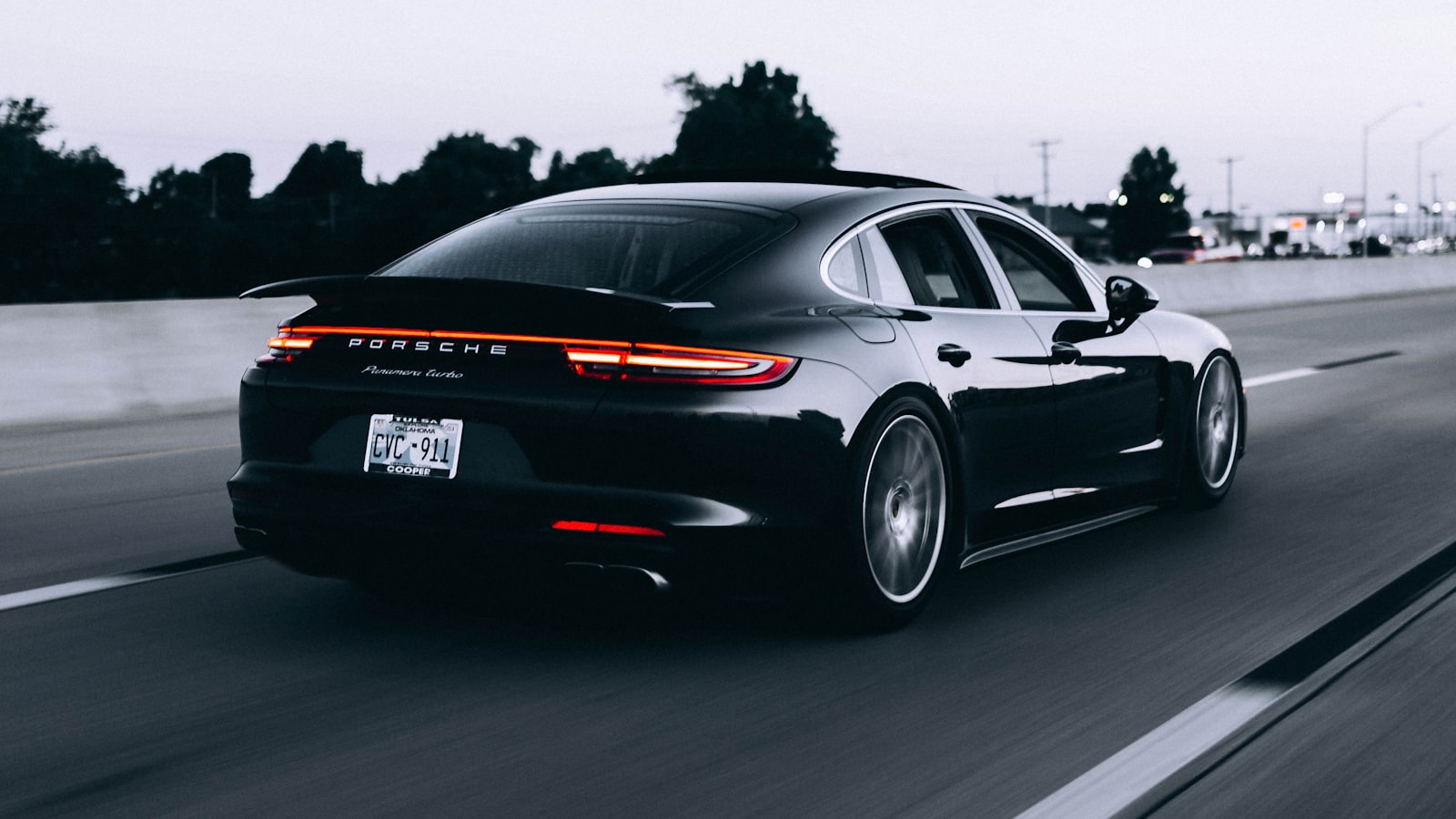 A car parked beside an open road stretching toward distant hills.