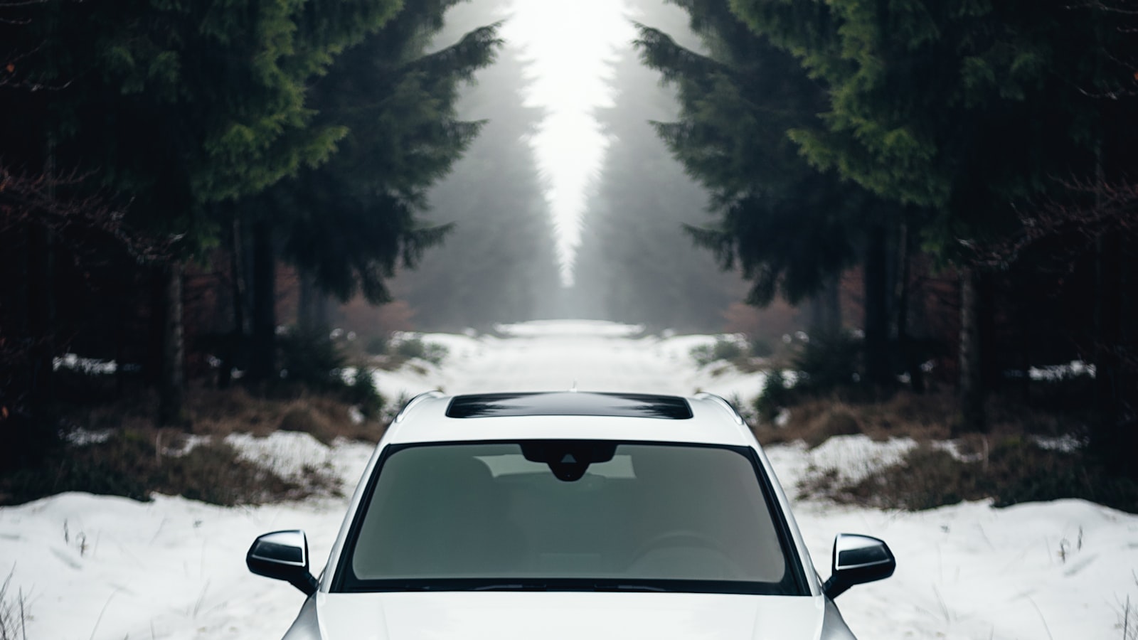 A car stopped on the shoulder of a road with its hood raised.