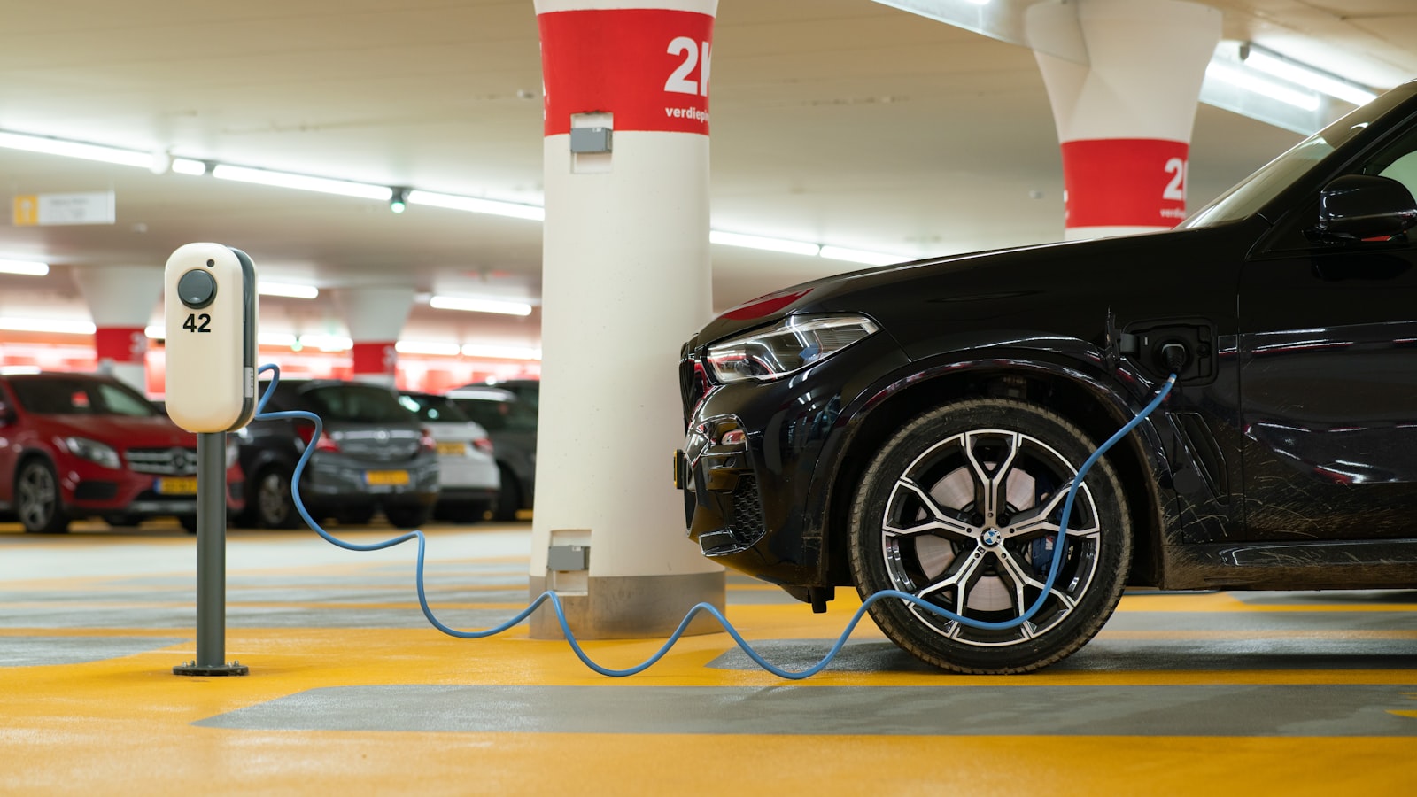 An electric car plugged in to charge on a home driveway.